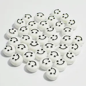 Close-up of 10mm white acrylic flat round beads with black smiley face pattern