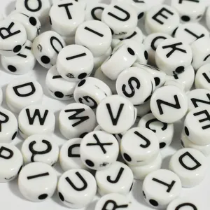 Close-up detail of 7mm white acrylic alphabet beads with black letters for DIY crafts