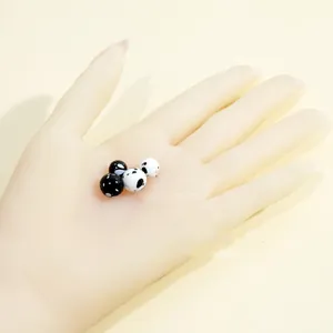 Detail view of 8mm black and white acrylic beads with splatter paint effect on a hand.