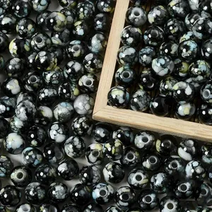 Close-up macro view of 8mm black acrylic beads with white splattered ceramic effect