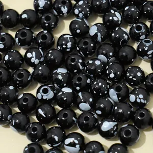 Macro view of 8mm black acrylic beads with white splattered ceramic effect