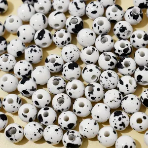 Macro detail of 8mm white acrylic beads with black splatter imitation ceramic effect