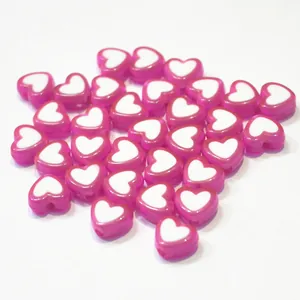 Close-up of glossy pink acrylic heart beads featuring white centers for DIY crafting