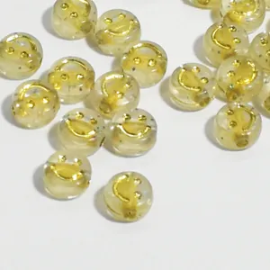 Primo piano di perline acriliche trasparenti da 10 mm con smiley dorato e glitter