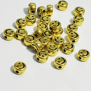 Primo piano di perline piatte rotonde in acrilico dorato con smiley nero per gioielli