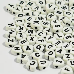 Close-up macro view of white heart shaped acrylic beads with black letter prints for DIY
