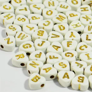 Macro view of 7mm white heart acrylic beads with gold embossed English alphabet letters