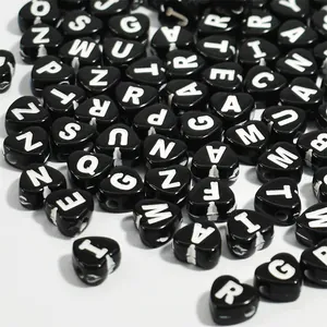 Macro view of 7mm black heart-shaped acrylic alphabet beads with white letters for DIY