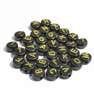 Dettaglio di perle acriliche nere da 10mm con lettere dorate per creazione gioielli.