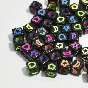 Macro detail of 6mm black acrylic cube beads with colorful heart and star patterns