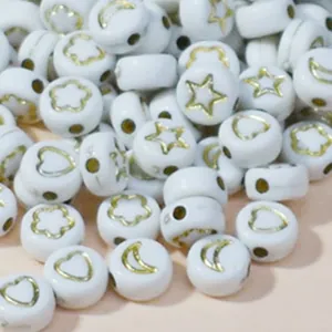 Close-up of 7mm white acrylic beads with gold star, moon, and heart patterns.