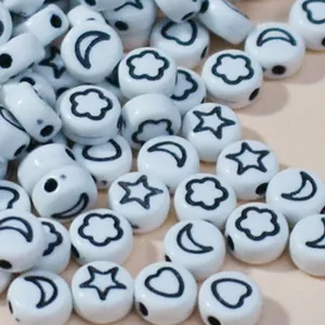Close-up of 7mm white acrylic beads with black star and moon symbols for DIY jewelry crafts.