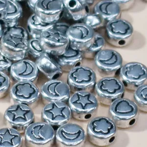 Macro view of 7mm silver acrylic beads with star and moon patterns for DIY crafting