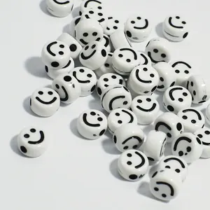 Macro detail of white acrylic round beads with black smiley face prints for DIY jewelry