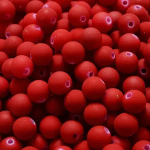 Macro detail of 6-10mm red matte acrylic beads with rubberized paint finish for DIY.