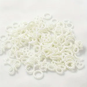 Close-up of 10-11mm white pearl charms in bow and ring shapes for DIY phone case decoration