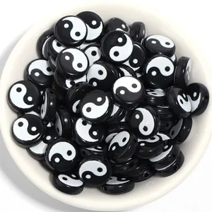 Close-up of black and white Yin Yang Tai Chi flat beads in a white bowl for DIY jewelry.