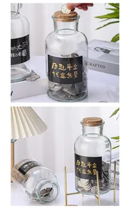 Detalle de hucha grande de cristal transparente con tapa de corcho y caligrafía