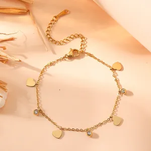 Macro view of gold stainless steel heart charm bracelet with sparkling zircons.
