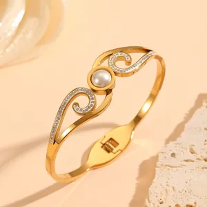 Close-up view of gold stainless steel jewelry bangle with pearl and crystal wings