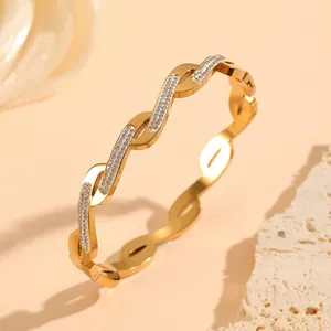 Detailed view of gold plated stainless steel wavy bangle with micro pavé crystal accents