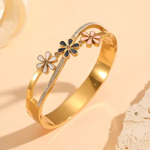 Detail of gold stainless steel bangle featuring enamel flowers and sparkling rhinestones.
