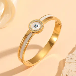 Detail view of gold evil eye bangle with rhinestones and white shell inlay for women