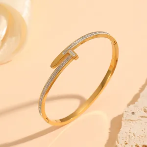 Detailed macro view of a golden stainless steel nail bangle paved with sparkling crystals.