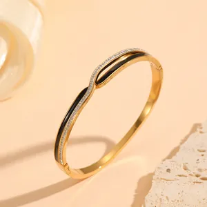 Detailed view of a gold-plated stainless steel bangle with black enamel and shiny rhinestones
