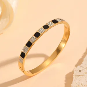 Close-up of gold-plated stainless steel bangle with black enamel and crystal squares