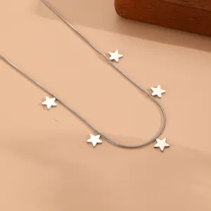 Macro detail view of a stainless steel snake chain necklace with silver star pendants