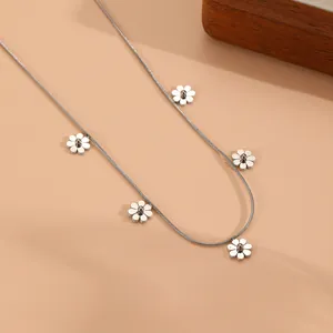 Macro view of dainty silver daisy flower charms on a stainless steel snake chain