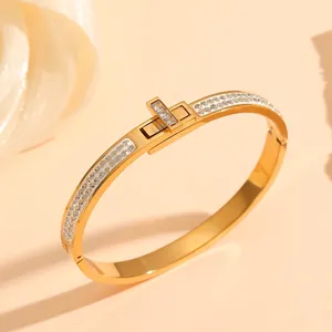 Close-up of gold titanium steel bangle with lock design and inset sparkling crystals