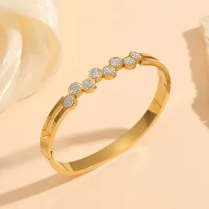 Detailed view of a gold titanium steel bangle with shimmering circular crystal accents.