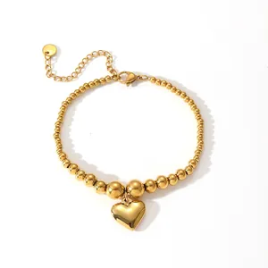 Nahaufnahme eines minimalistischen goldenen Titanstahl-Perlenarmbands mit Herzanhänger