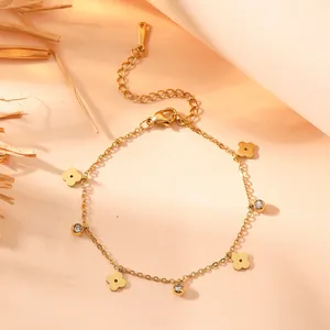 Detail of titanium steel gold bracelet with delicate flower charms and cubic zirconia stones.