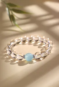 Detailopname van een witte kristallen kralenarmband met een centrale aquamarijnsteen