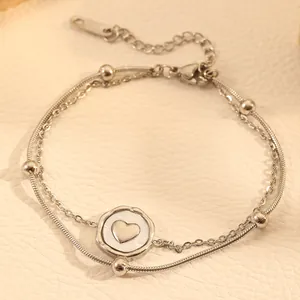 Close-up detail of a double-layered stainless steel anklet featuring heart pendant.