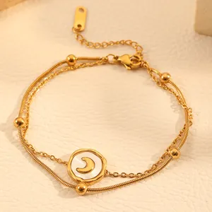 Close-up detail of a double-layered gold anklet featuring a crescent moon charm.