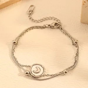 Close-up of double-layered titanium steel anklet with moon pendant and snake chain