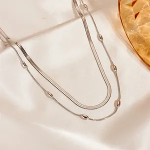 Double-layered silver snake chain anklet with polished beads on elegant satin background