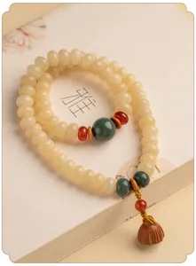 Detailopname van crème Bodhi-wortelkraal armband met een houten lotuspeul bedeltje eraan