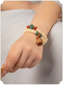 Detail van een dubbele streng Bodhi-wortel armband met lotusbedel om de pols.