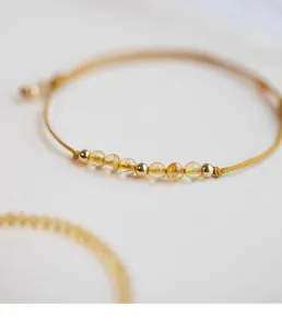 Macro view of natural citrine and gold beads on a yellow woven bracelet