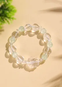 Dettaglio del bracciale in cristallo bianco con ciondolo a volpe scolpita su sabbia beige