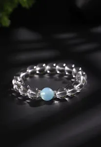Detail van een kristallen armband met een lichtblauwe aquamarijn kraal in focus.