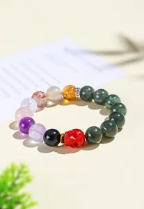 Gedetailleerde opname van 12mm groene rutielkwarts armband met een rode schedel kraal detail.