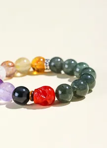 Detailweergave van 12mm natuurlijke groene rutielkwarts armband met rode schedelkraal.