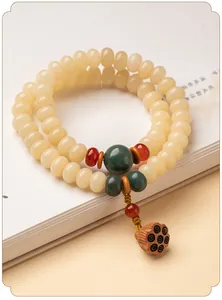 Detail eines cremegelben Bodhi-Wurzel-Armbands mit Lotusanhänger und grünen Perlen