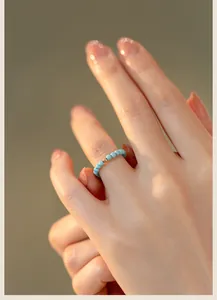 Macro view of 2mm turquoise bead ring with a 14k gold accent on a model's finger